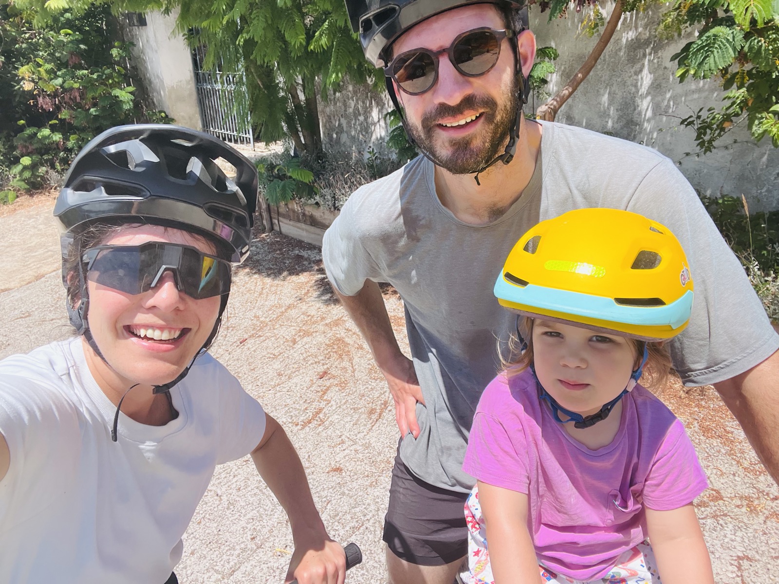 Dois pais e a filha com capacetes durante um passeio de bicicleta em família
